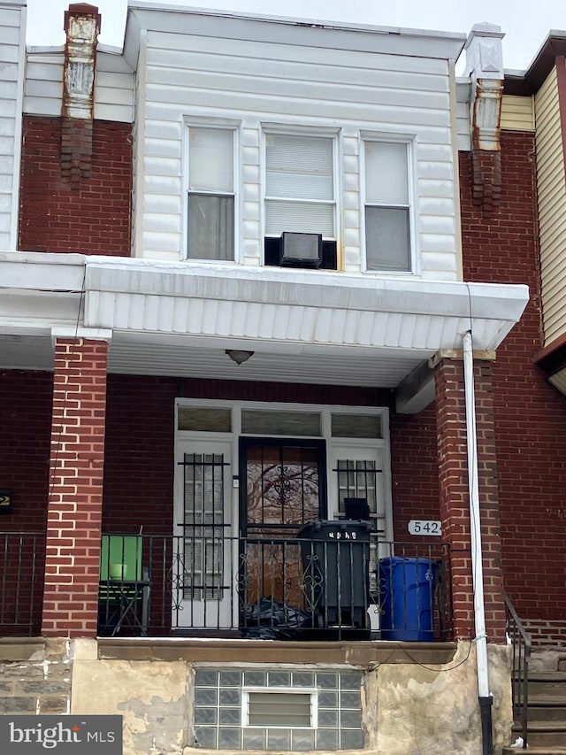 view of exterior entry with a porch and brick siding