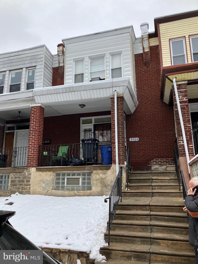 multi unit property featuring a porch and brick siding