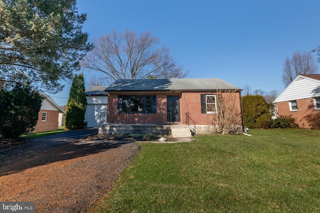 single story home with driveway, brick siding, and a front yard