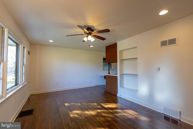 spare room with dark wood-type flooring, visible vents, and baseboards