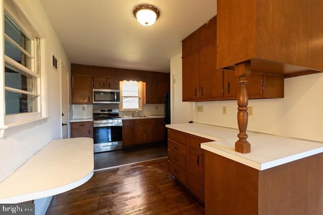 kitchen with stainless steel appliances, visible vents, light countertops, dark wood-style floors, and brown cabinetry