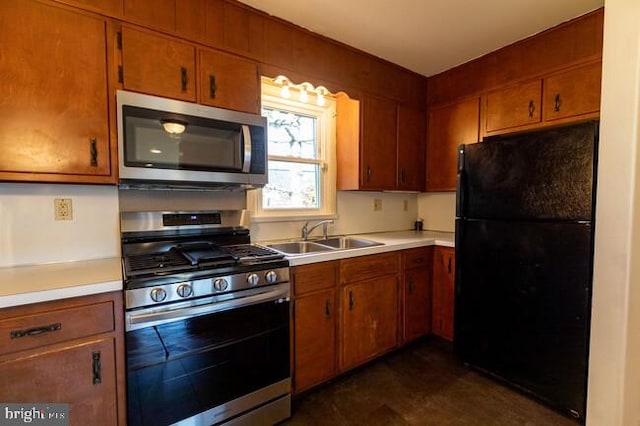 kitchen with stainless steel appliances, brown cabinetry, a sink, and light countertops