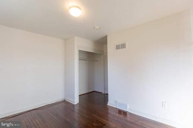 unfurnished bedroom featuring a closet, visible vents, baseboards, and wood finished floors