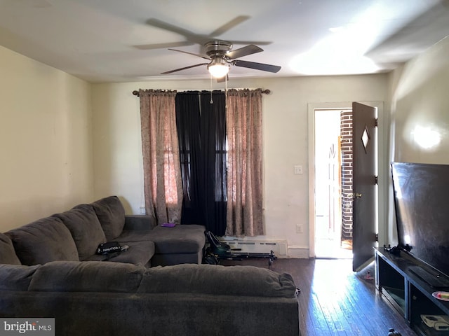 living area featuring a ceiling fan, baseboard heating, a healthy amount of sunlight, and hardwood / wood-style floors