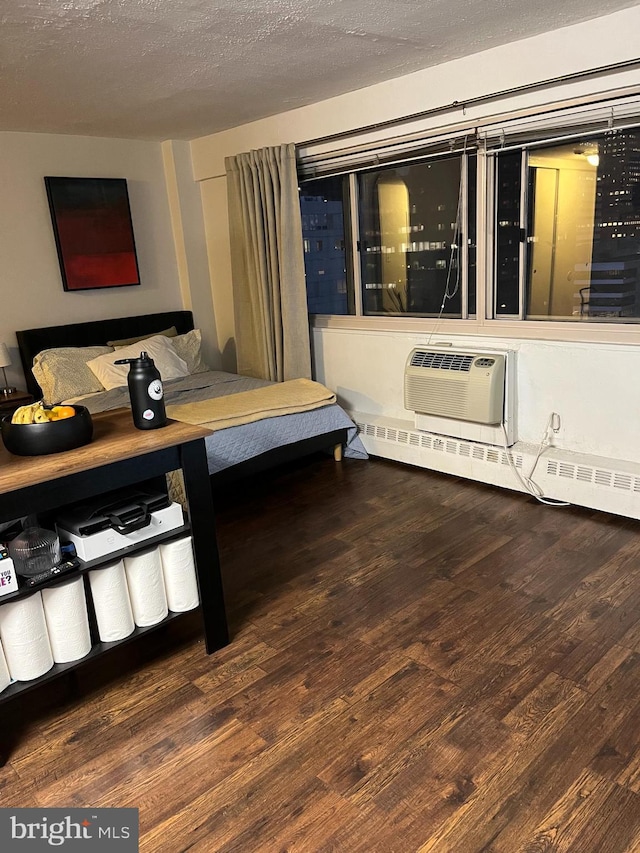 bedroom with a textured ceiling, a wall mounted air conditioner, and wood finished floors