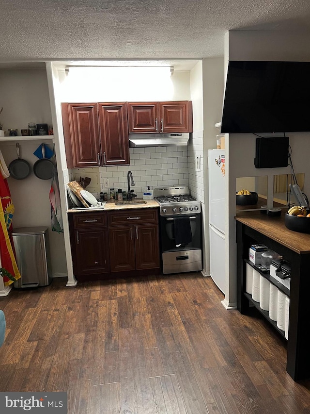 kitchen featuring under cabinet range hood, a sink, light countertops, stainless steel gas range, and dark wood finished floors