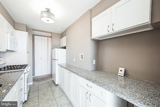 kitchen featuring light tile patterned floors, white appliances, white cabinetry, and light stone countertops