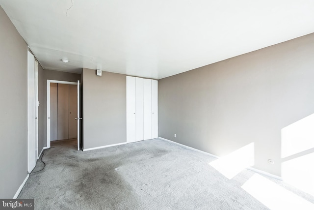 unfurnished bedroom featuring carpet floors, baseboards, and a closet