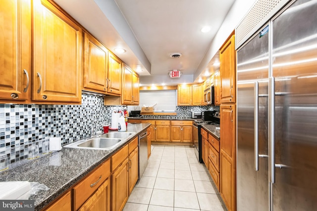 kitchen featuring light tile patterned floors, tasteful backsplash, brown cabinets, stainless steel appliances, and a sink