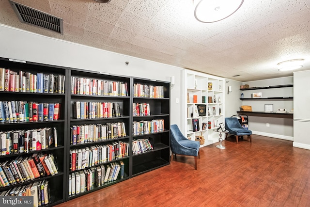 living area with baseboards, visible vents, and wood finished floors