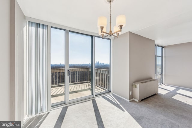 carpeted spare room with baseboards, a wall of windows, a wealth of natural light, and an inviting chandelier