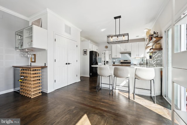 kitchen featuring crown molding, stainless steel range, open shelves, freestanding refrigerator, and a peninsula