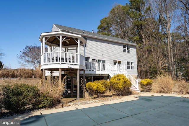 rear view of house featuring stairs, a deck, and roof with shingles