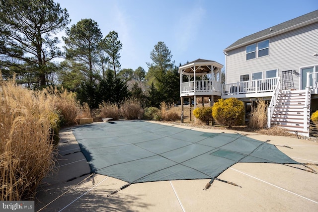 view of swimming pool featuring a covered pool, stairway, a wooden deck, and a diving board