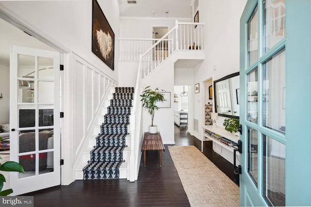 foyer entrance featuring visible vents, stairway, a high ceiling, and wood finished floors