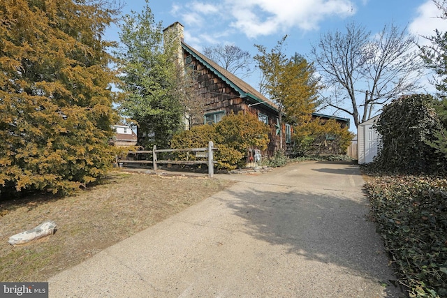 view of property exterior featuring a chimney and fence