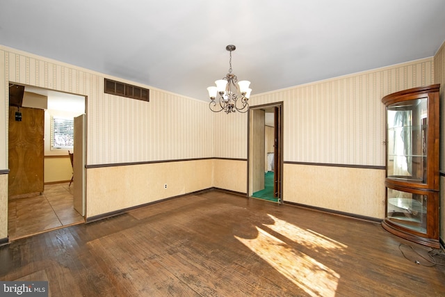 spare room featuring wainscoting, visible vents, and wallpapered walls