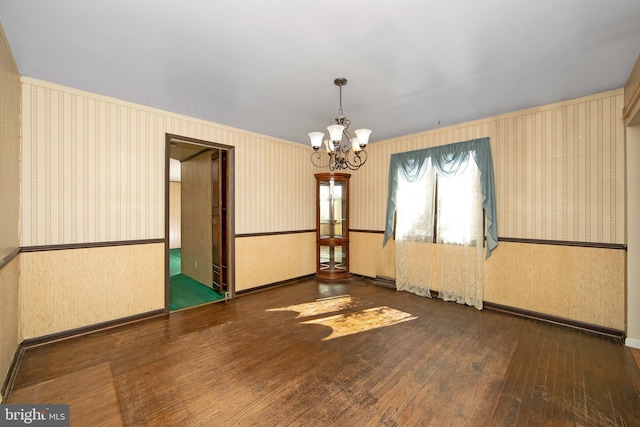 spare room with wood-type flooring, wainscoting, an inviting chandelier, and wallpapered walls