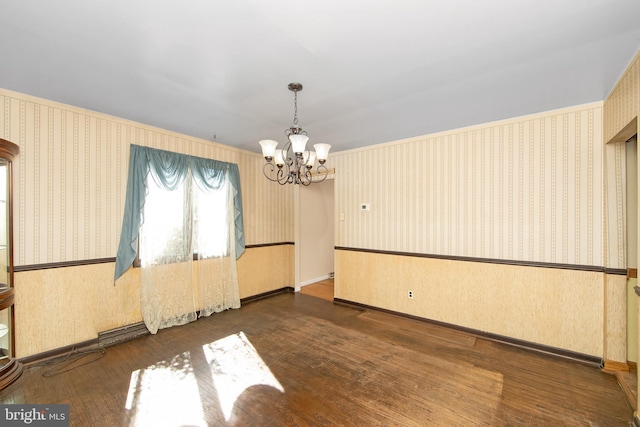 unfurnished room with a chandelier, baseboards, wood finished floors, and wallpapered walls