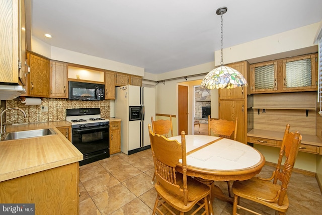 kitchen with gas range oven, light countertops, a sink, white fridge with ice dispenser, and black microwave