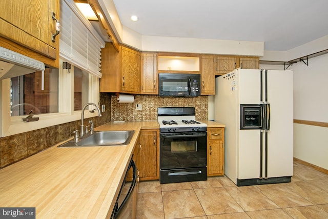 kitchen with light countertops, backsplash, brown cabinetry, a sink, and black appliances