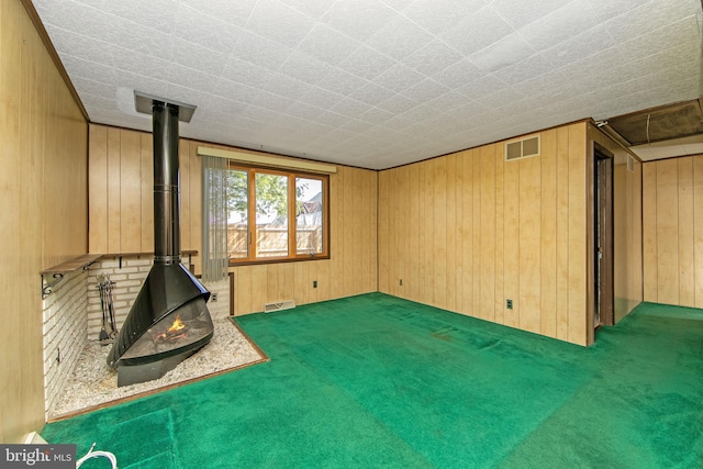 unfurnished living room with visible vents, a wood stove, and wooden walls