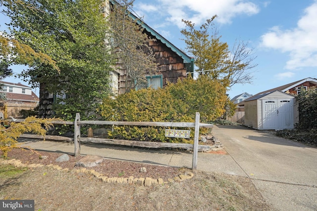 view of property exterior featuring a storage shed, fence, and an outdoor structure