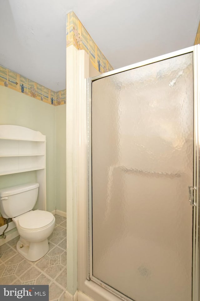 full bath featuring tile patterned flooring, baseboards, a shower stall, and toilet