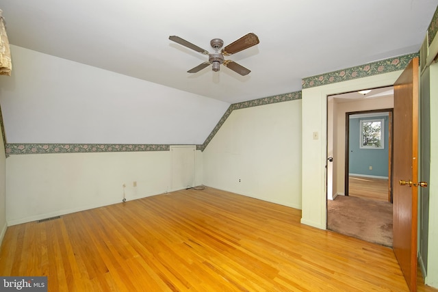 additional living space featuring a ceiling fan, lofted ceiling, visible vents, and light wood-style flooring