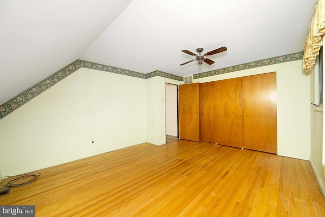 unfurnished bedroom featuring vaulted ceiling, a ceiling fan, and light wood-style floors