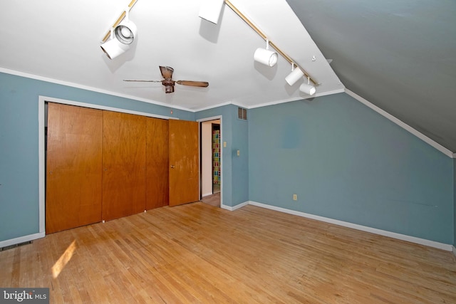 unfurnished bedroom with ornamental molding, lofted ceiling, baseboards, and wood finished floors