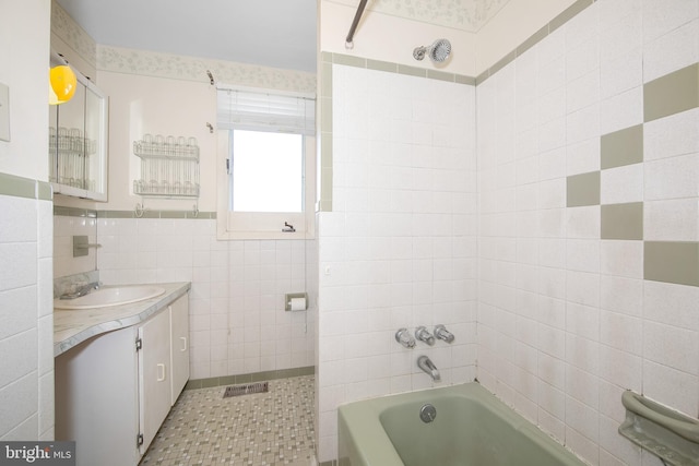 full bath featuring visible vents, vanity, tile walls, shower / bathing tub combination, and tile patterned floors