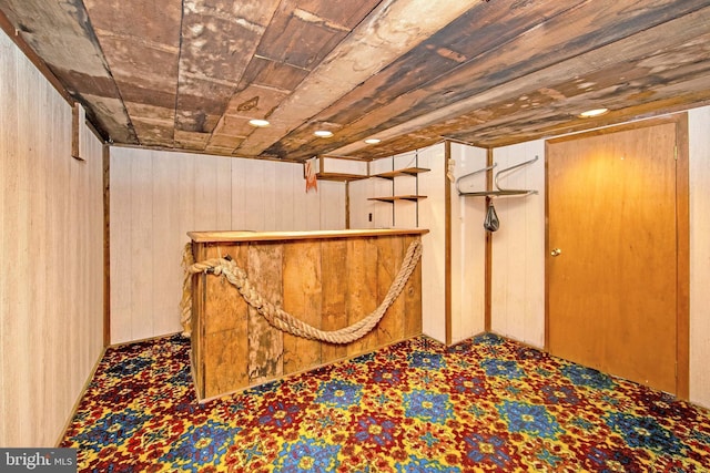 finished basement featuring a dry bar, wooden ceiling, and wood walls