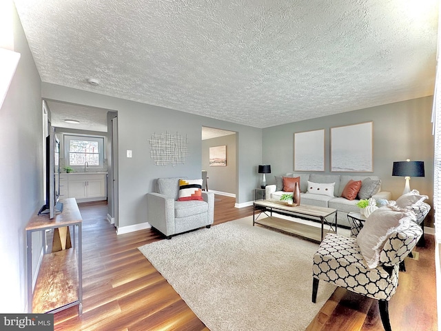 living area with a textured ceiling, wood finished floors, and baseboards