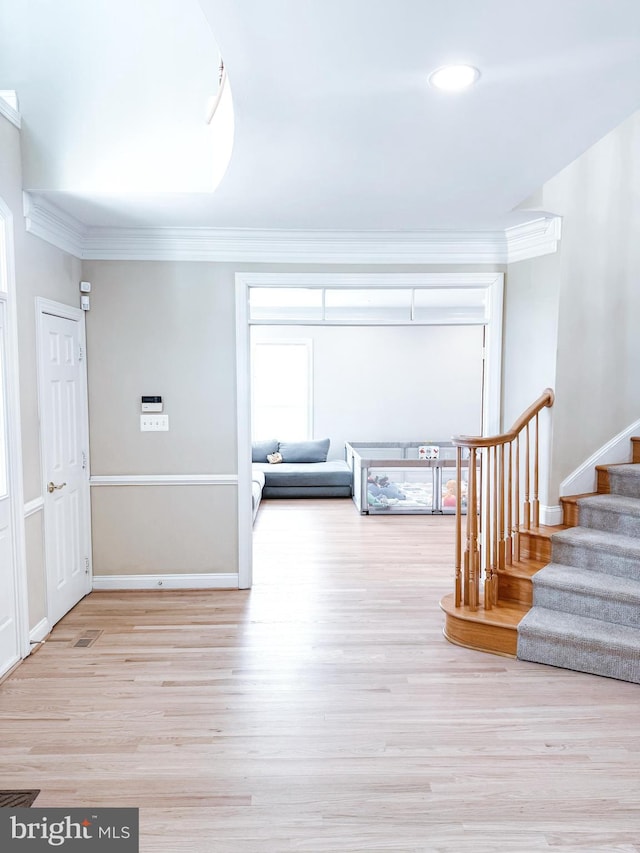 corridor with wood finished floors, crown molding, baseboards, and stairs