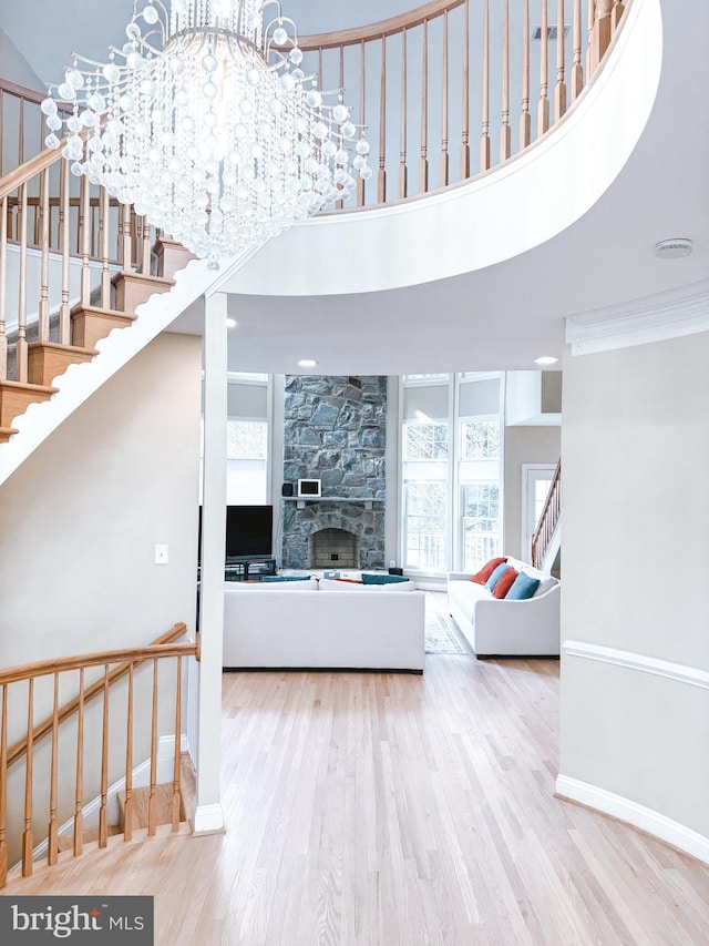 living room featuring a fireplace, stairway, a towering ceiling, and wood finished floors