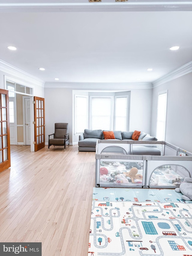 living room with light wood-style floors, recessed lighting, ornamental molding, and french doors