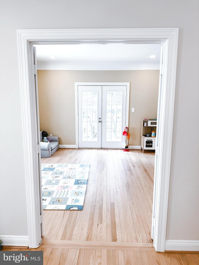 doorway to outside featuring wood-type flooring, ornamental molding, baseboards, and french doors