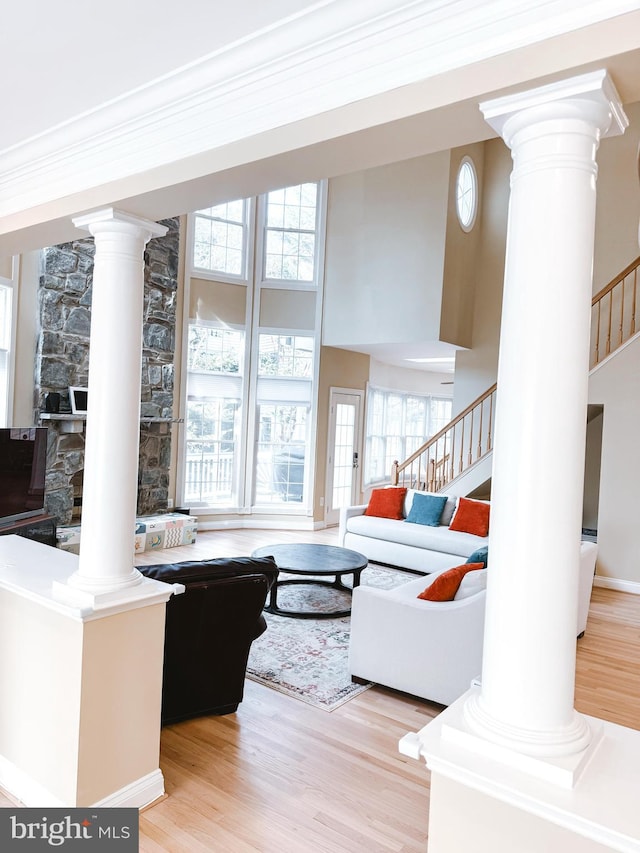 living room featuring ornate columns, stairway, and wood finished floors