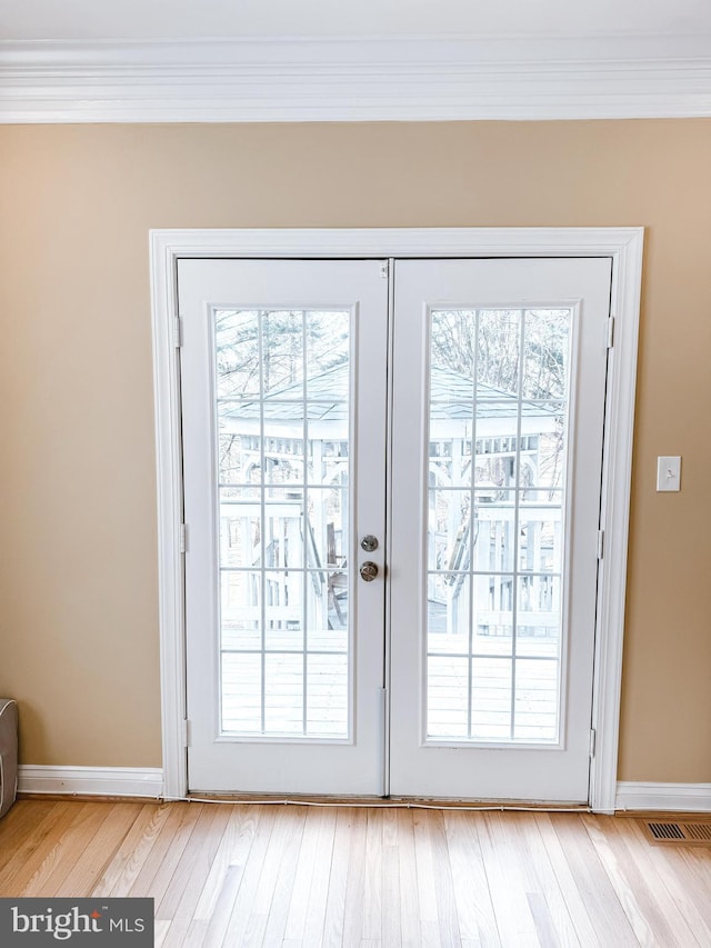 entryway featuring light wood-style flooring, baseboards, crown molding, and french doors