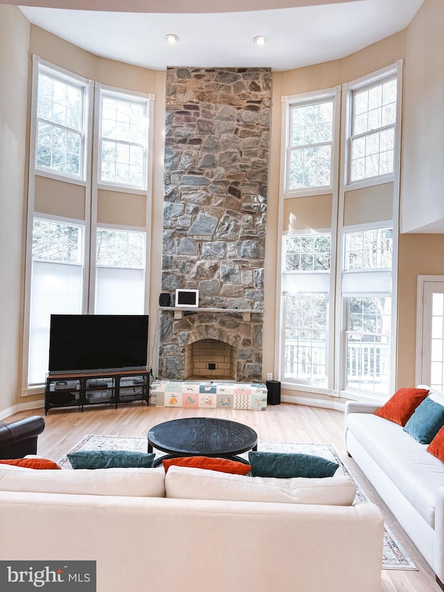 living area featuring plenty of natural light, a fireplace, a high ceiling, and wood finished floors