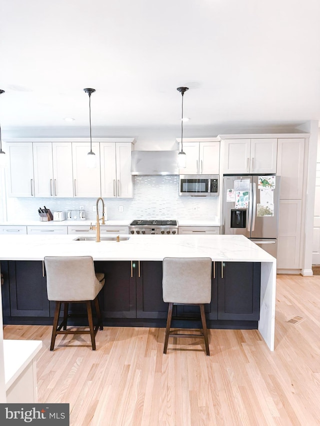 kitchen featuring appliances with stainless steel finishes, white cabinetry, a sink, and light wood finished floors