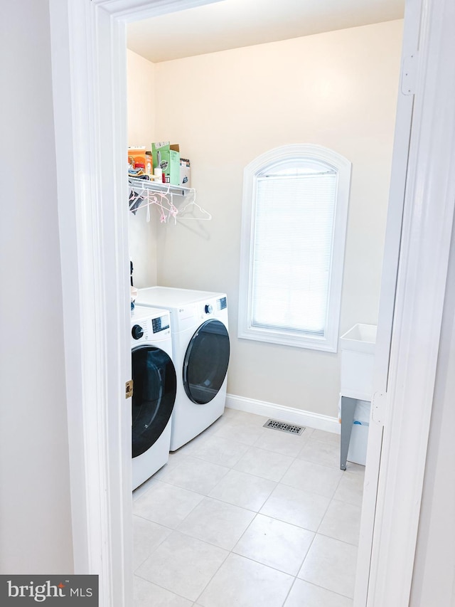 laundry room featuring light tile patterned floors, visible vents, washer and dryer, laundry area, and baseboards