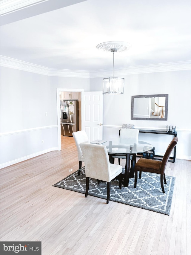 dining area with a chandelier, crown molding, baseboards, and wood finished floors