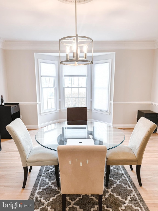 dining area with ornamental molding, baseboards, an inviting chandelier, and wood finished floors