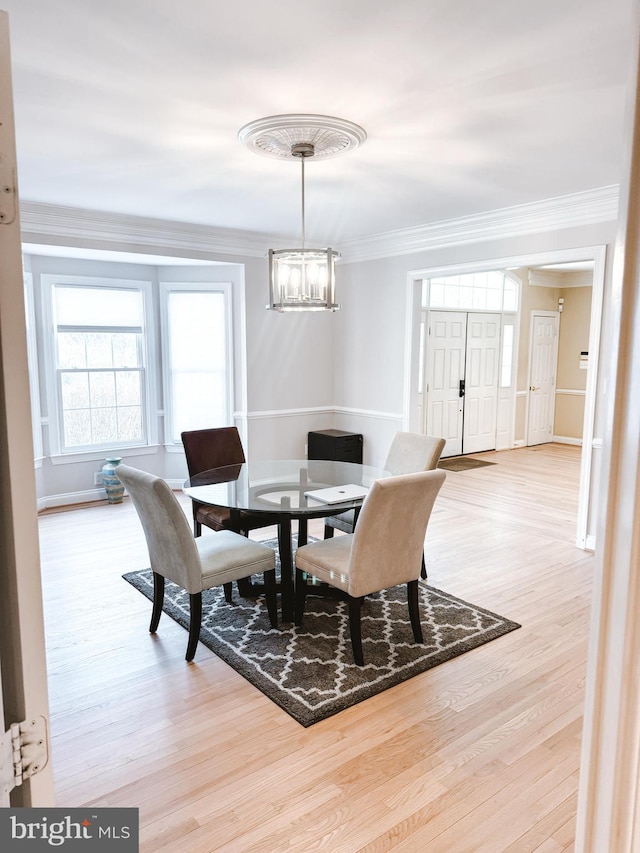 dining area with ornamental molding, a chandelier, baseboards, and wood finished floors