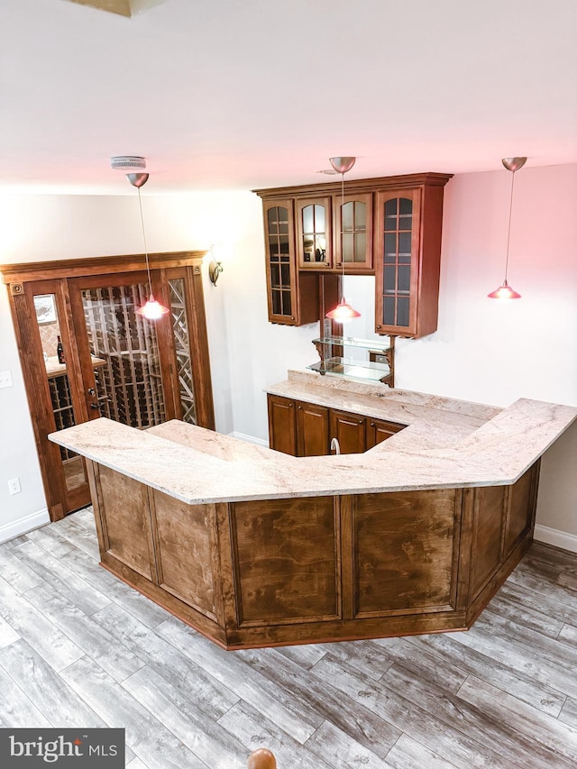 bar featuring pendant lighting, light wood-style flooring, and baseboards