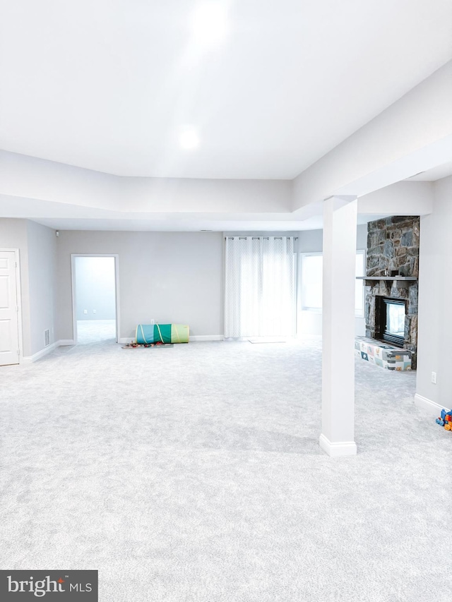 below grade area featuring carpet, baseboards, and a stone fireplace