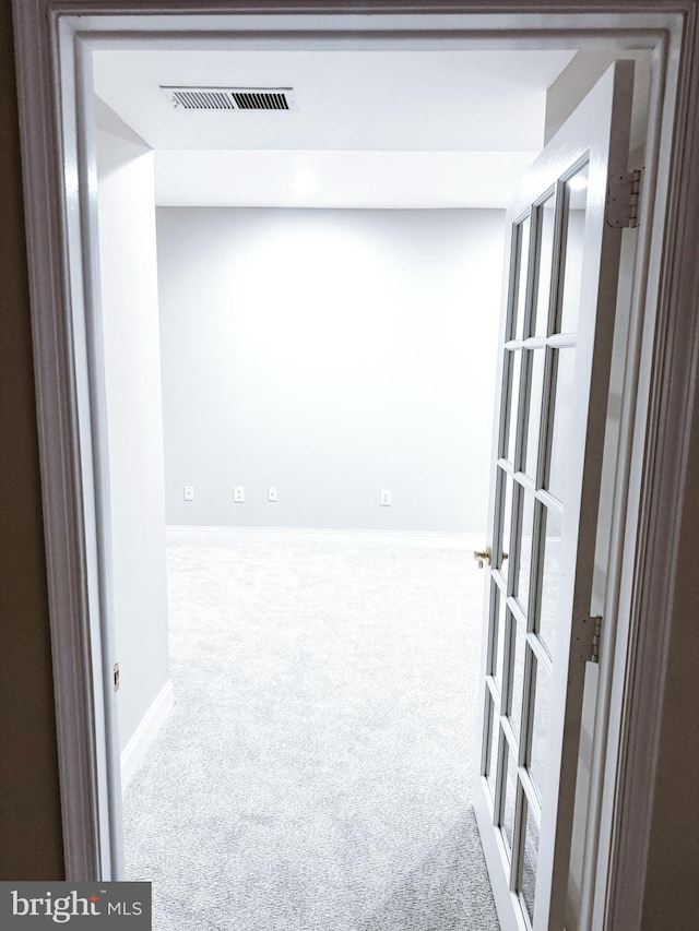 hallway featuring carpet, visible vents, and baseboards