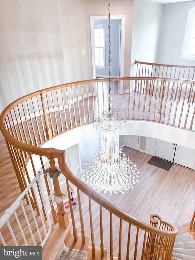 stairs with wood finished floors and a notable chandelier